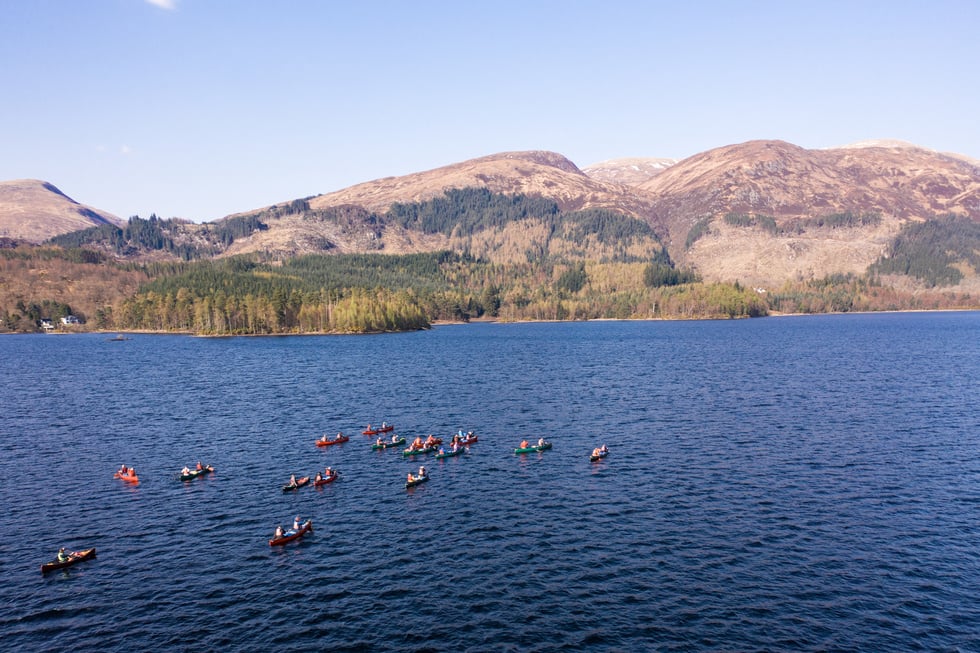 Large Group of Canoeists on a Lake With Mountain Landscape